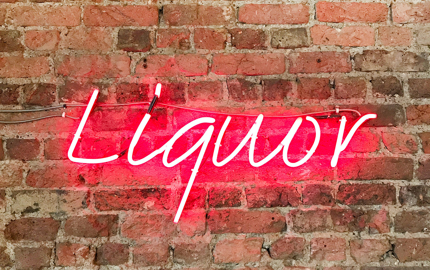 neon sign 'liquor' on brick wall